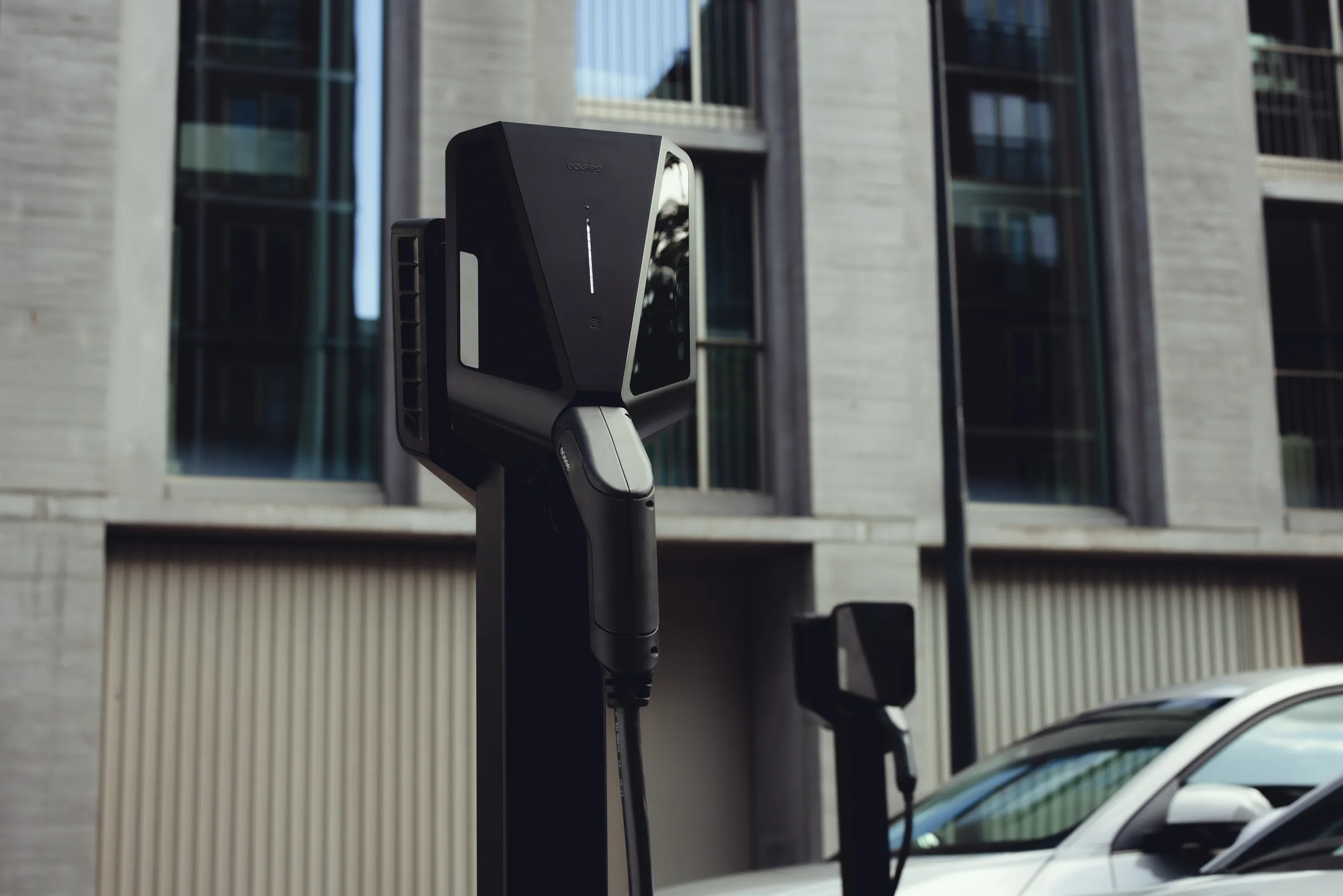 Close-up of a black Easee EV charger mounted on a pole on a city street